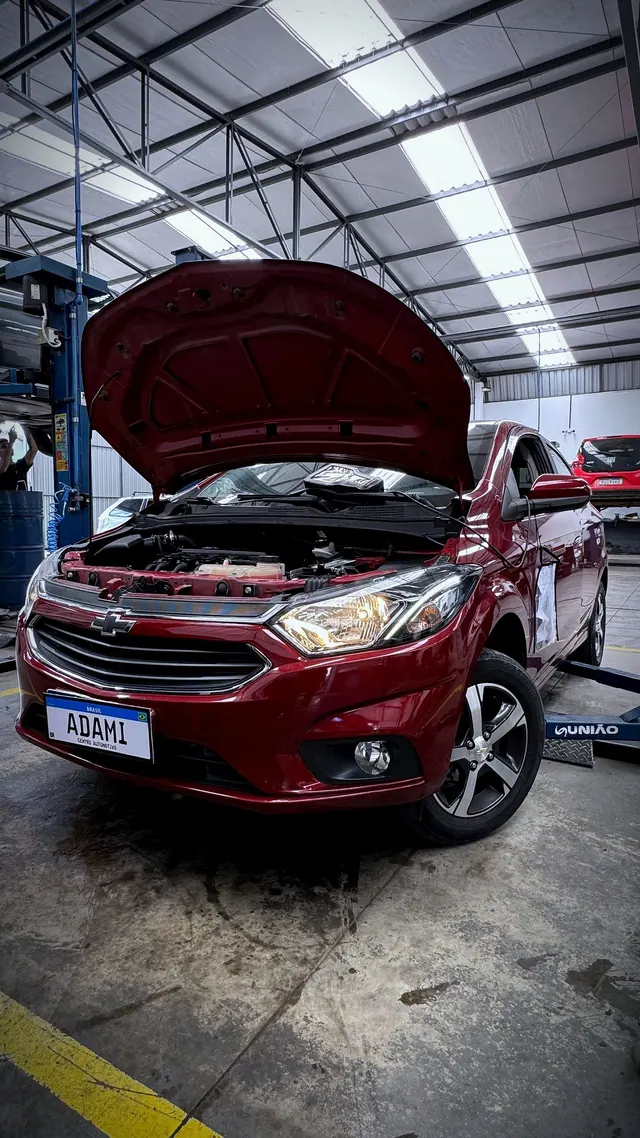 Chevrolet Onix com capô aberto em manutenção